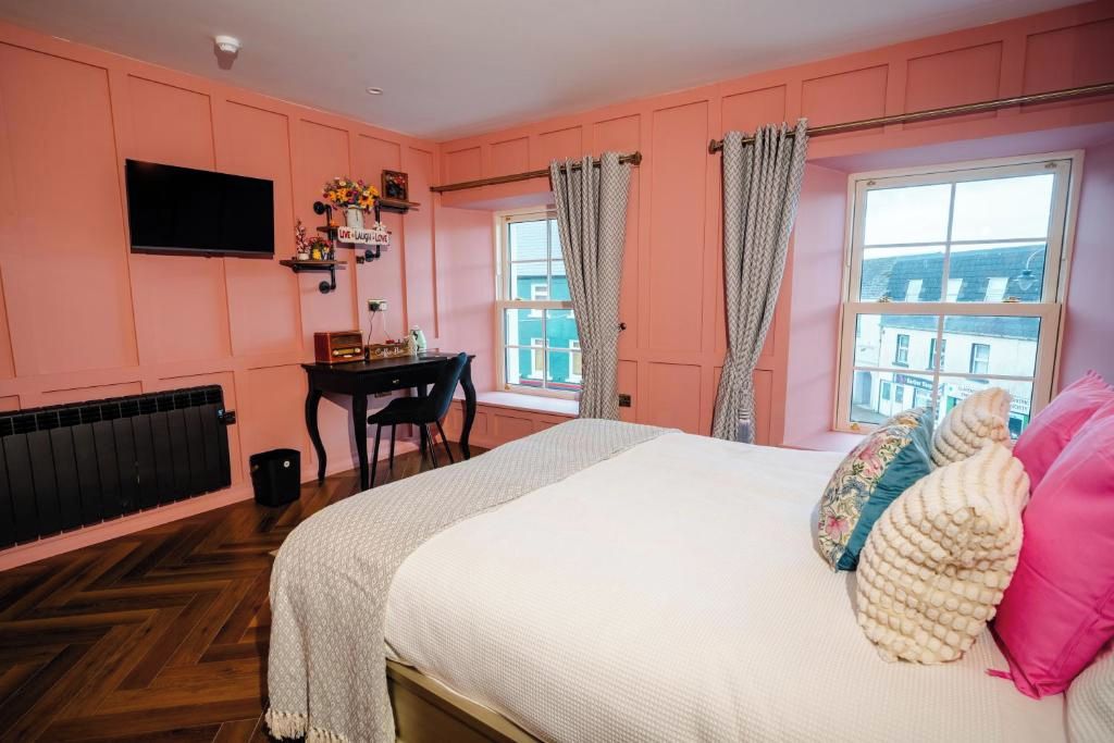 Een slaapkamer met een bed, een bureau, een televisie en een raam met gordijnen.
