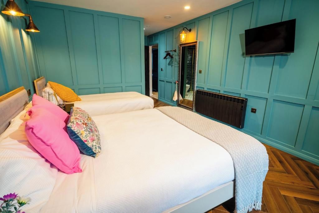 A bedroom with two beds, a TV mounted on the wall, and a mirror.
