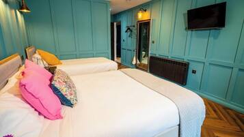 A bedroom with two beds, a TV mounted on the wall, and a mirror.