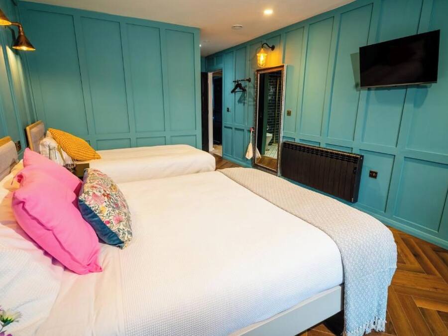 Un dormitorio con dos camas, un televisor montado en la pared y un espejo.