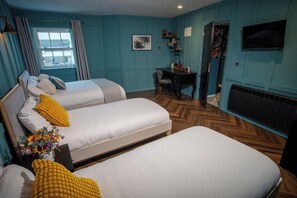 A room with two beds, a desk, a chair, a TV, and a window with curtains.
