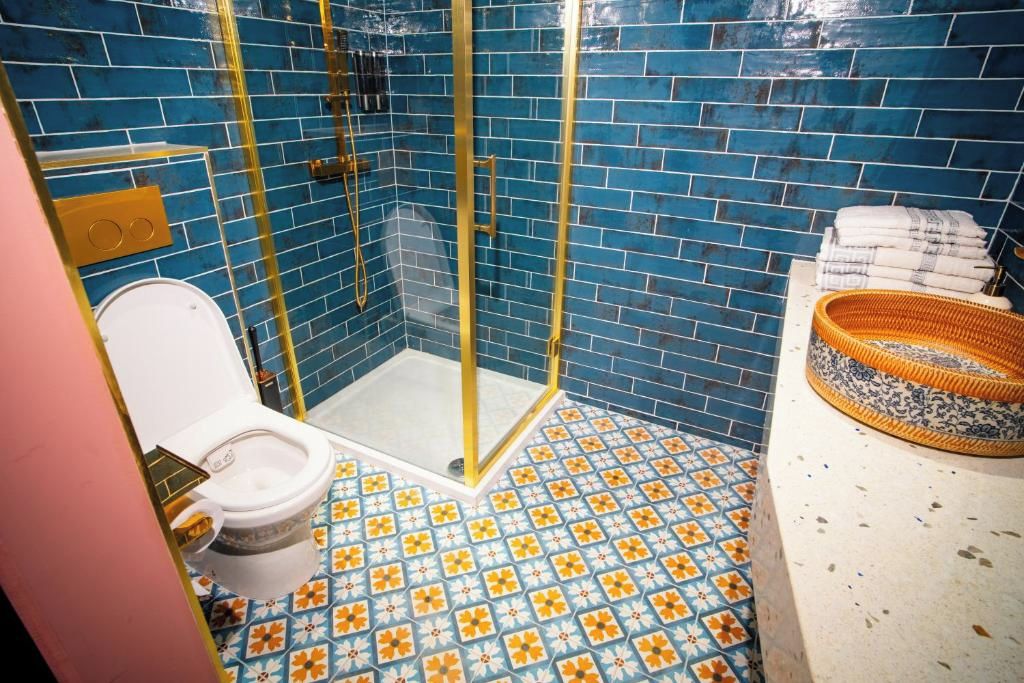 Une salle de bain avec des toilettes blanches, une douche dotée d’une paroi en verre et un carrelage décoré.