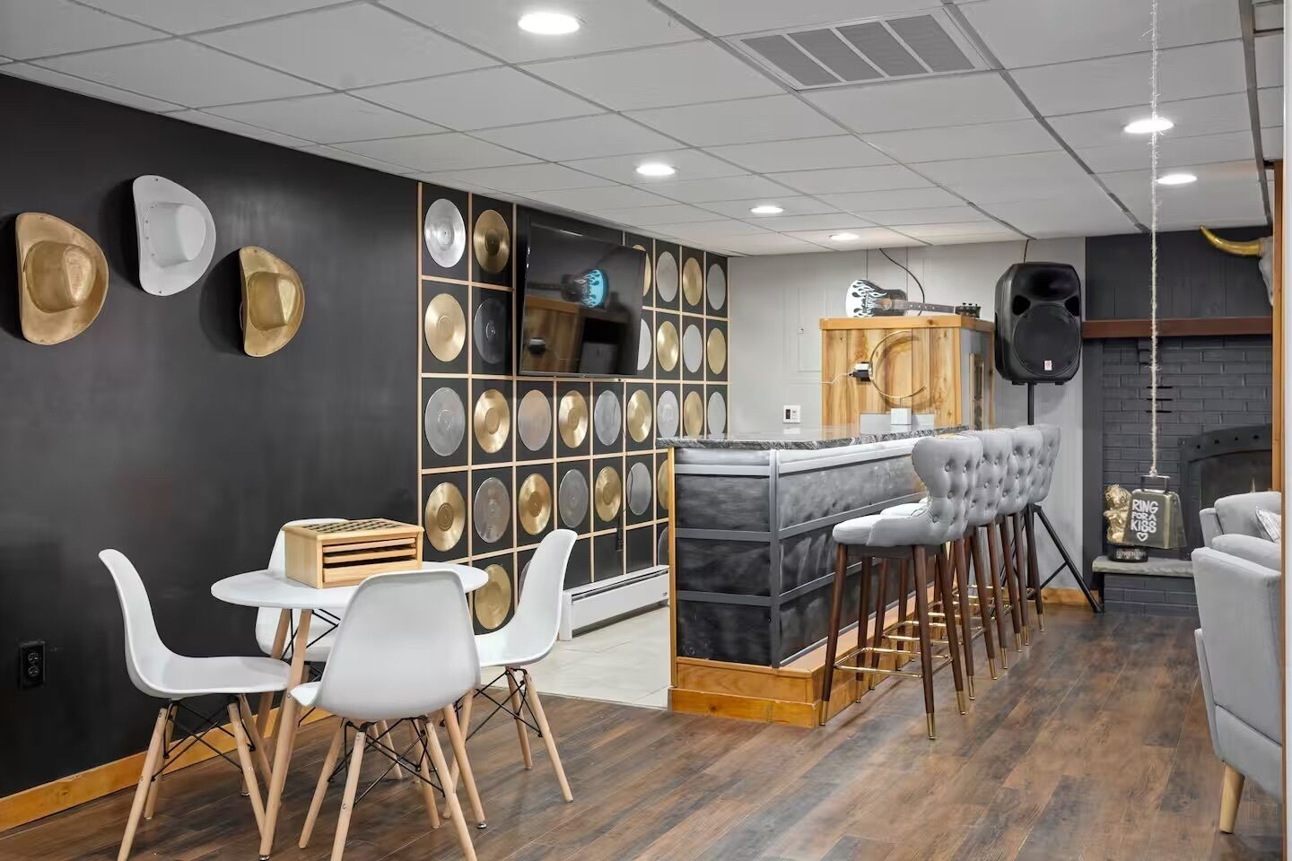 A modern bar area with a marble countertop, white bar stools, and a wall adorned with decorative plates.