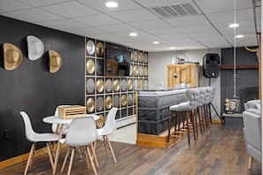 Un área de bar moderna con una encimera de mármol, taburetes blancos y una pared decorada con platos ornamentales.