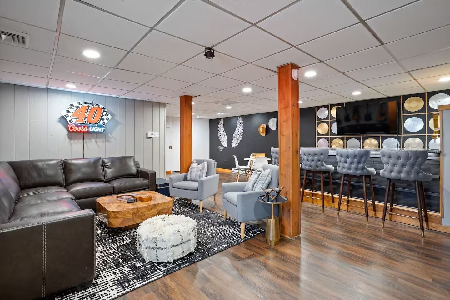 A modern lounge area with leather sofas, a bar with stools, and a decorative wall with circular patterns.