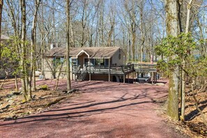 A cabin with a porch and a covered deck area, surrounded by trees. - Honky Tonk Karaoke! Hot Tub - Sauna - 5 min wlk 2 lake (Lake Harmony)