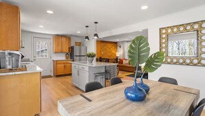 A modern kitchen with wooden cabinets, a central island, and pendant lighting. - Honky Tonk Karaoke! Hot Tub - Sauna - 5 min wlk 2 lake (Lake Harmony)