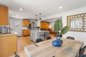 A modern kitchen with wooden cabinets, a central island, and pendant lighting. - Honky Tonk Karaoke! Hot Tub - Sauna - 5 min wlk 2 lake (Lake Harmony)