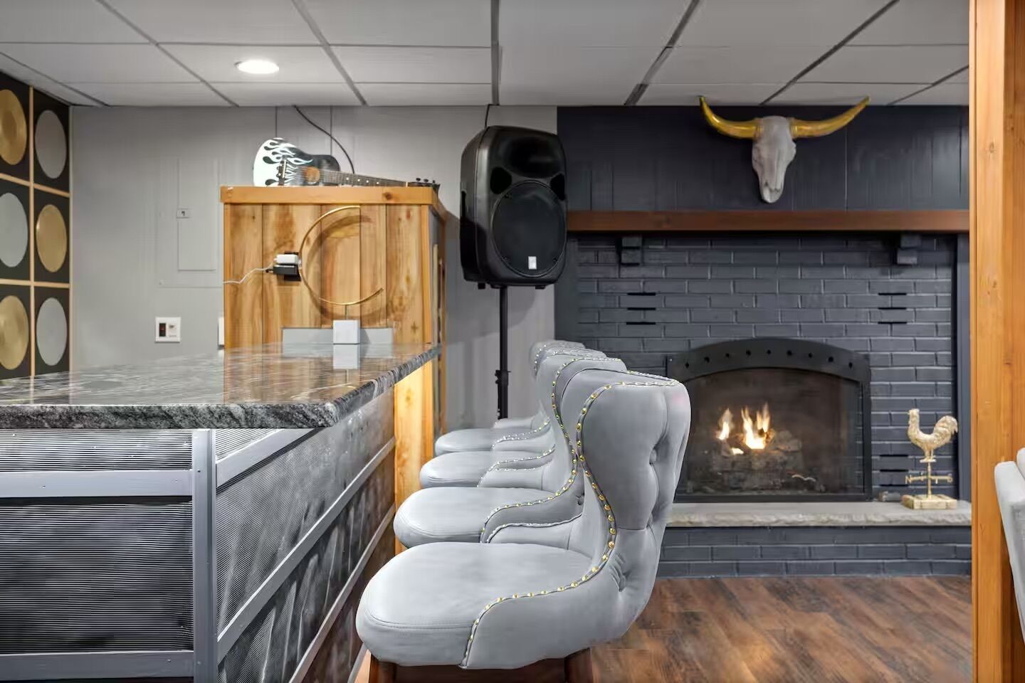 A bar area with a fireplace, seating, and a speaker.