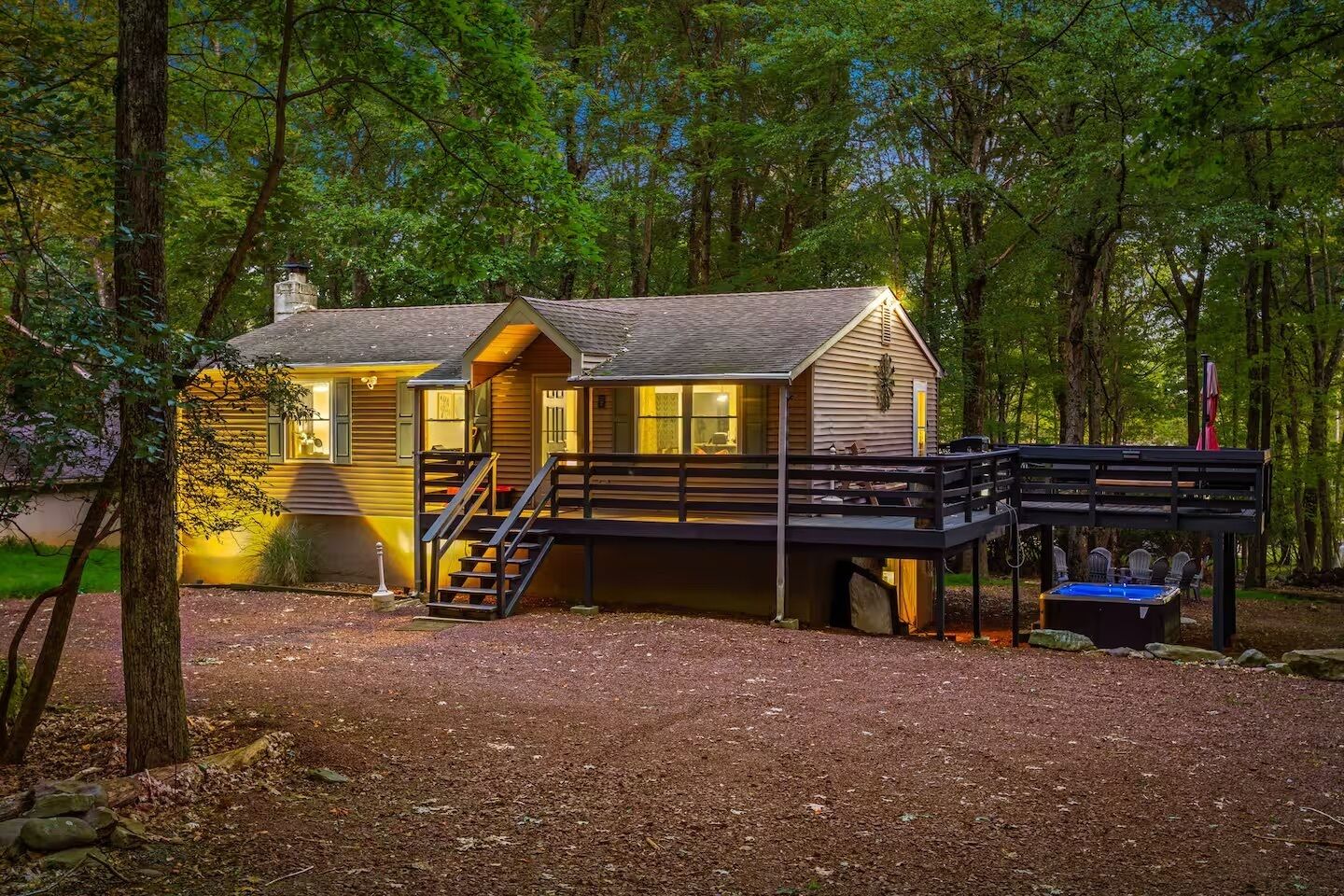 A cabin with a deck, stairs, and a small outdoor seating area.