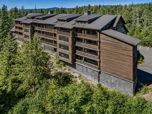 A multi-story wooden building with balconies, surrounded by dense forest. - Yocum Ridge Condo 204 at South Grand Lodge | Best Mt. Hood View (Government Camp)