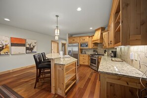 A kitchen with wooden cabinets, granite countertops, a stainless steel refrigerator, and a built-in oven. - Yocum Ridge Condo 204 at South Grand Lodge | Best Mt. Hood View (Government Camp)