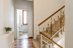 A staircase with a wooden handrail and metal balusters, leading to a bathroom with a toilet and a window. - Casa La Conchiglia - Casa la Conchiglia (Porto Recanati)