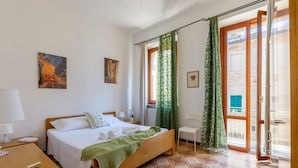 Een hotelkamer met een bed, een bureau, een stoel, een raam met gordijnen en kunstwerken aan de wanden.