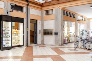 Amplo espaço interno com piso ladrilhado, loja de sapatos à esquerda e bicicleta estacionada à direita.