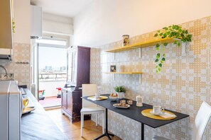 Cozinha moderna com área de refeições, destacando uma janela grande, forno embutido e máquina de café.