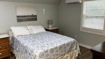 A bedroom with a bed, nightstands, a lamp, a ceiling fan, and a window with blinds.