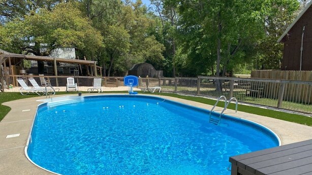 Ein rechteckiger Swimmingpool mit Sprungbrett und Basketballkorb.