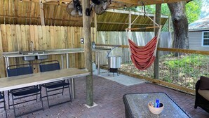 Eine Terrasse im Freien mit einem Holztisch und -stühlen, einer Hängematte und einem Backsteinboden.