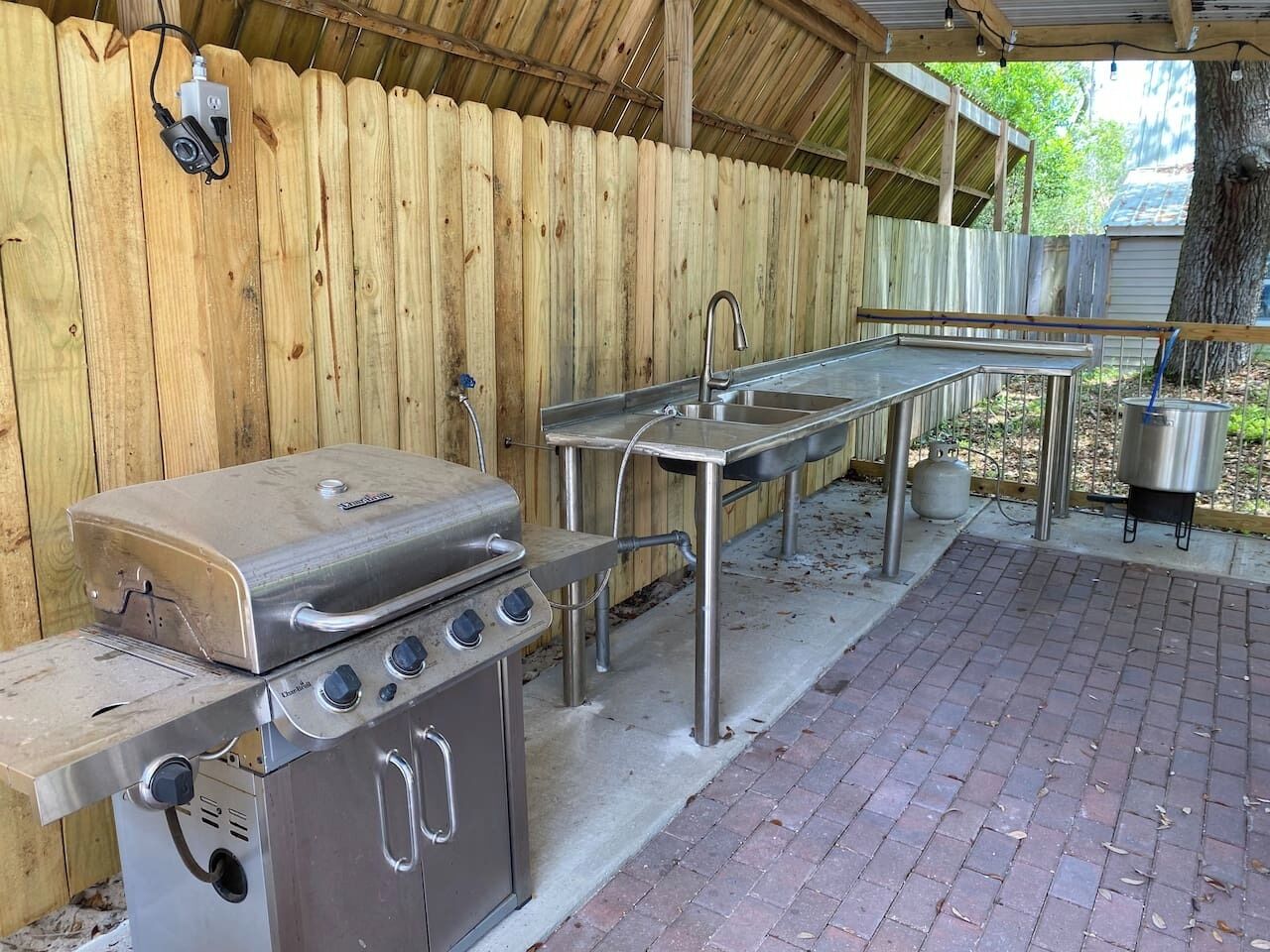 An outdoor kitchen area with a grill, sink, and gas stove.