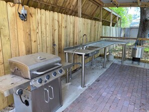 Un área de cocina exterior con una parrilla, pileta y estufa a gas.