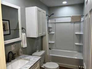 Un baño con ducha, inodoro, lavabo y espejo.