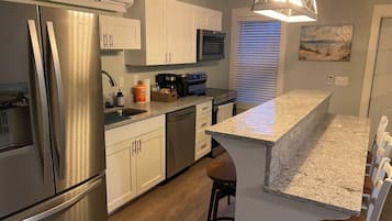 A modern kitchen with stainless steel appliances, a granite countertop, and a bar area.