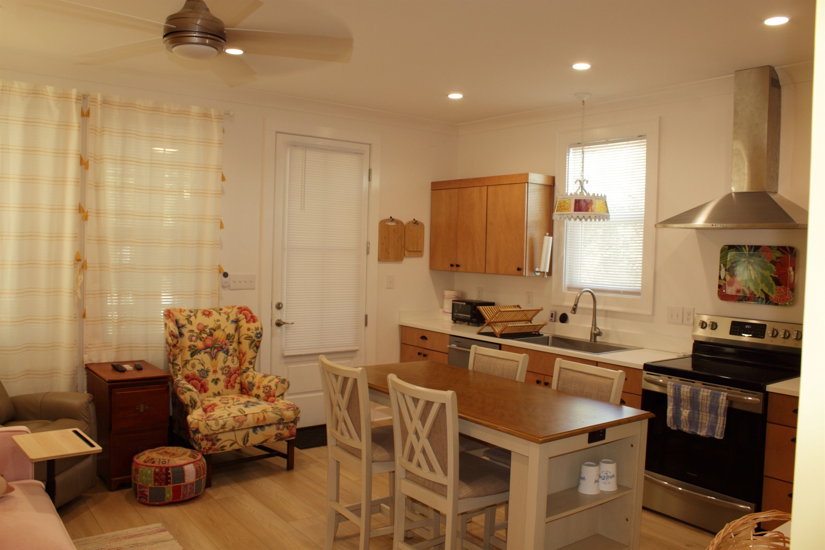A compact kitchen with a dining area, wooden cabinets, a built-in oven, and a ceiling fan.