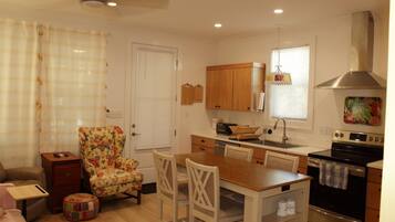 A compact kitchen with a dining area, wooden cabinets, a built-in oven, and a ceiling fan.