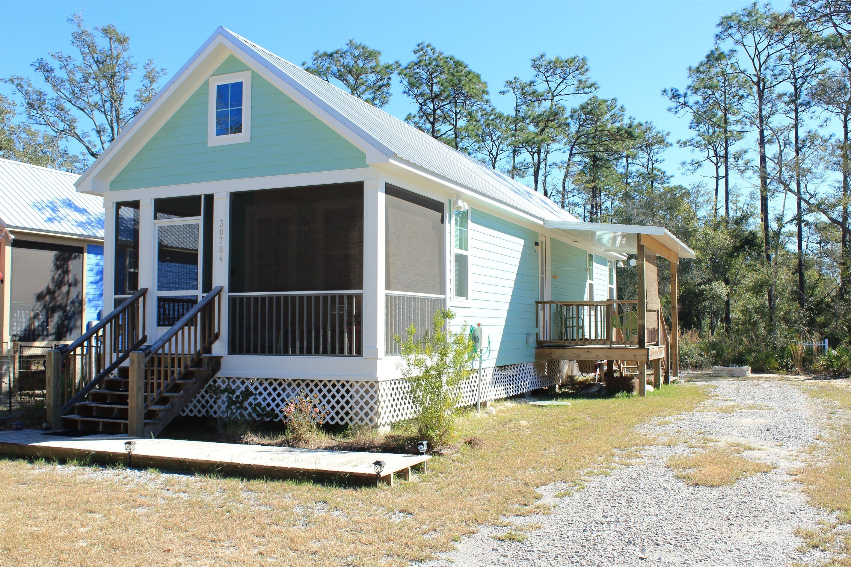 A two-story house with a porch, a covered deck, and a gravel driveway.