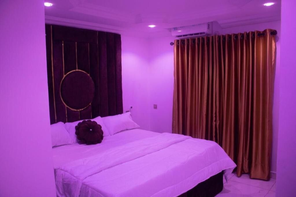 Un dormitorio con cama, cortinas y un adorno circular en la pared.