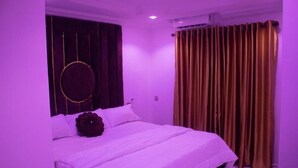 Un dormitorio con cama, cortinas y un adorno circular en la pared.