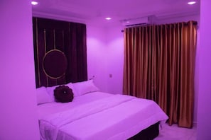 Una camera da letto con un letto, tende e un elemento decorativo circolare al muro.