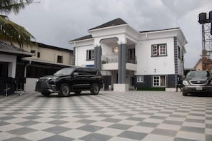 A two-story building with a balcony, a carport, and a checkered floor.