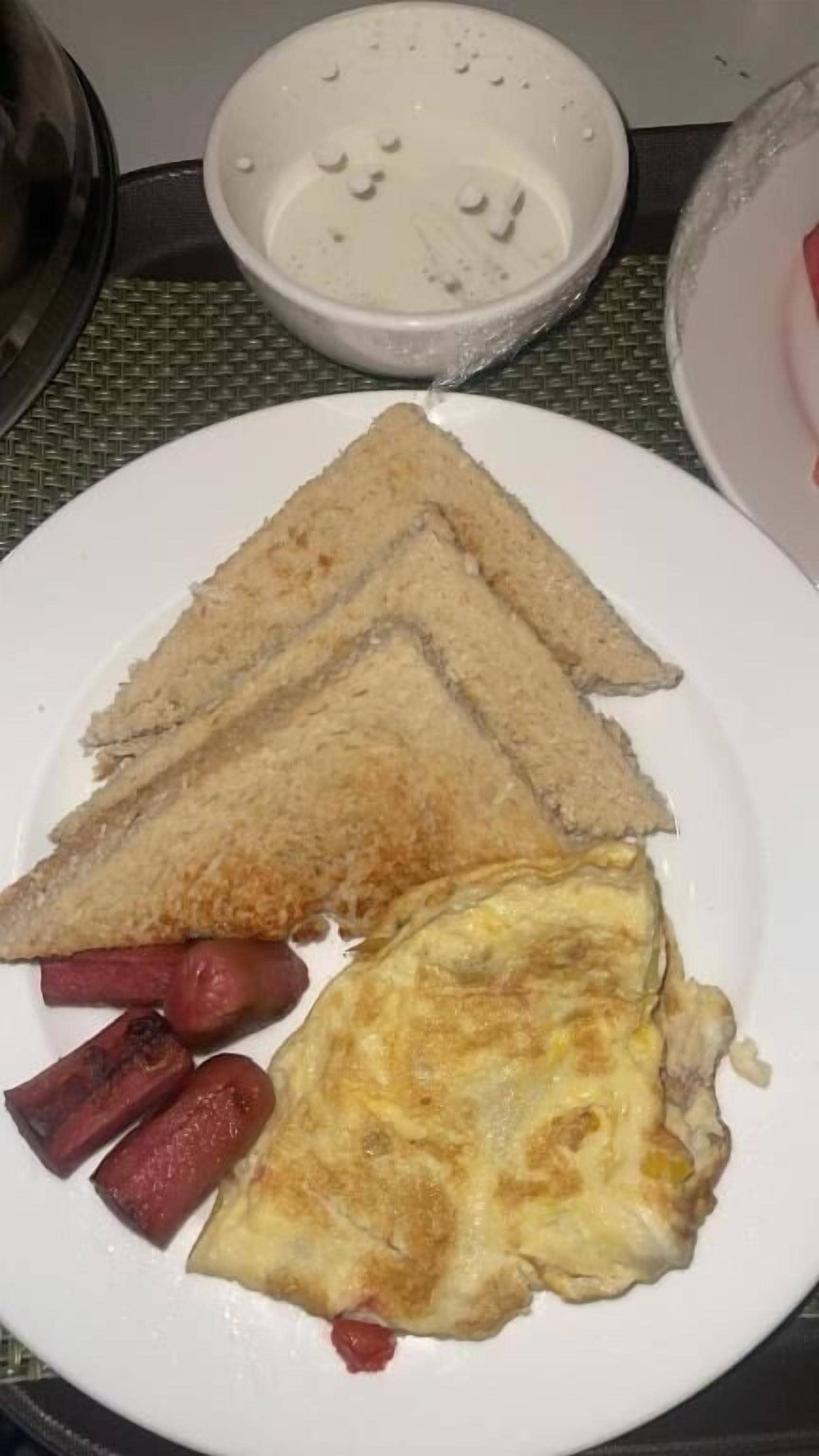 Un plato con tostadas, salchichas y una tortilla.