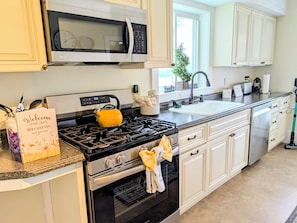 A kitchen with a stove, microwave, and oven, a sink, and cabinets. - The 1860 Farmhouse: A Peaceful New England Retreat (Barrington)