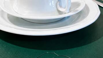 Un juego de tetera y taza blancos sobre un mantel verde con texto en relieve.