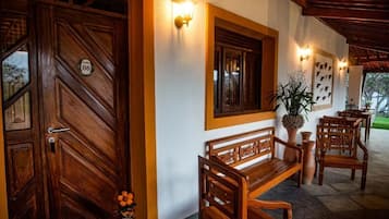 A wooden door with a number plaque, a bench, and wall-mounted lights.