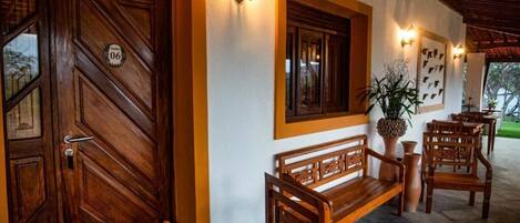 A wooden door with a number plaque, a bench, and wall-mounted lights.
