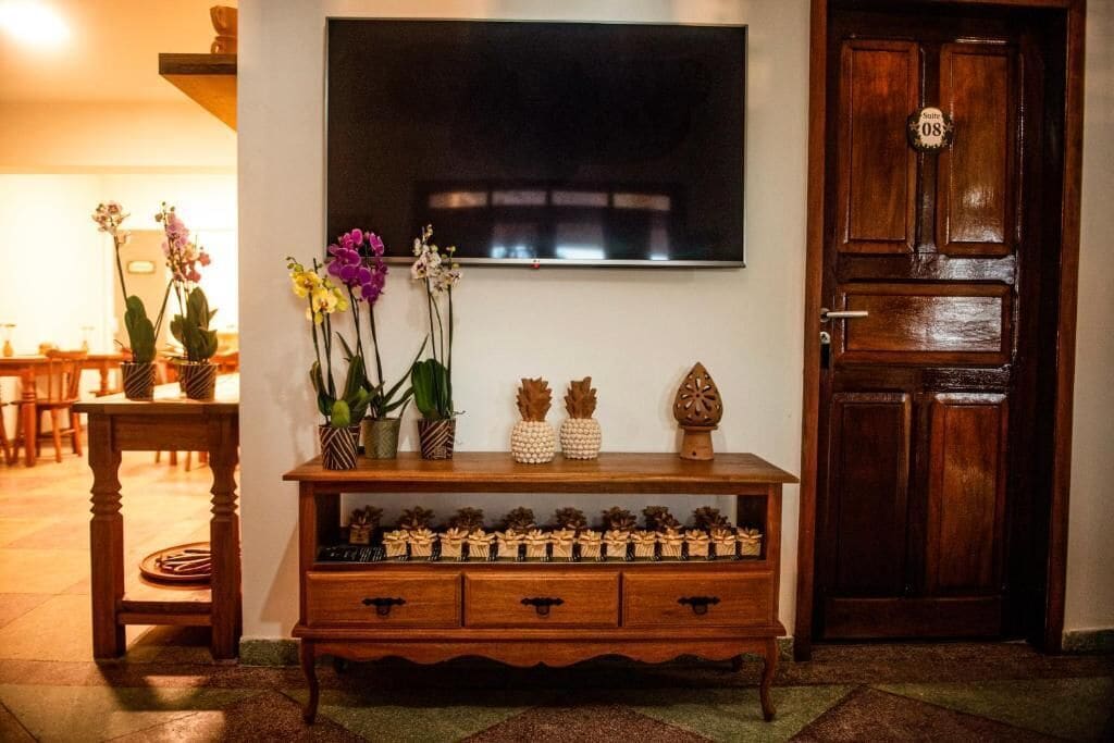 A wooden console table with decorative items and a television mounted on the wall.