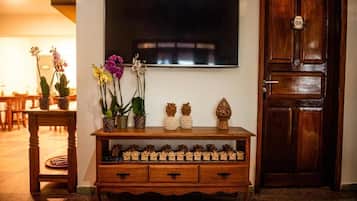 A wooden console table with decorative items and a television mounted on the wall.