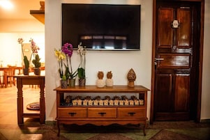 Um console de madeira com objetos decorativos e uma televisão fixada na parede.