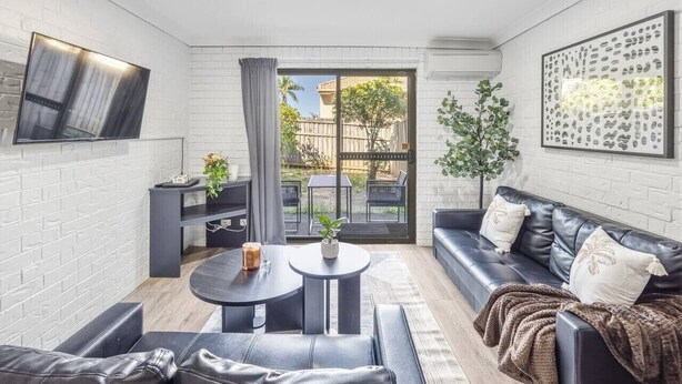 A modern living room with a flat-screen TV, a sofa, a coffee table, and a dining area. - Affordable townhouse Retreat| Pool| Prime Location (Eight Mile Plains)