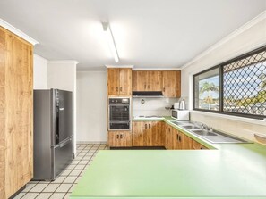 Cocina moderna con armarios de madera, un refrigerador de acero inoxidable, un horno y una ventana con vistas.