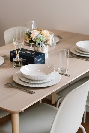 A dining table set with white plates, a glass, and a box of reed sticks. - Central Locate|City View| Walk to South Bank & CBD (South Brisbane)