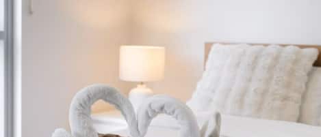 A bed with a brown textured blanket, a white pillow, and a lamp on a bedside table.