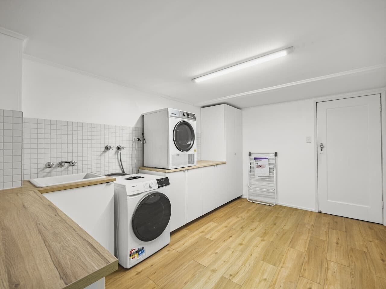 Un cuarto de lavandería con dos lavadoras, un lavamanos y una puerta.
