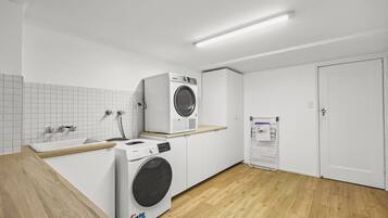Un cuarto de lavandería con dos lavadoras, un lavamanos y una puerta.