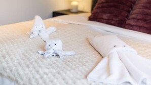 A neatly made bed with white towels and a red pillow.