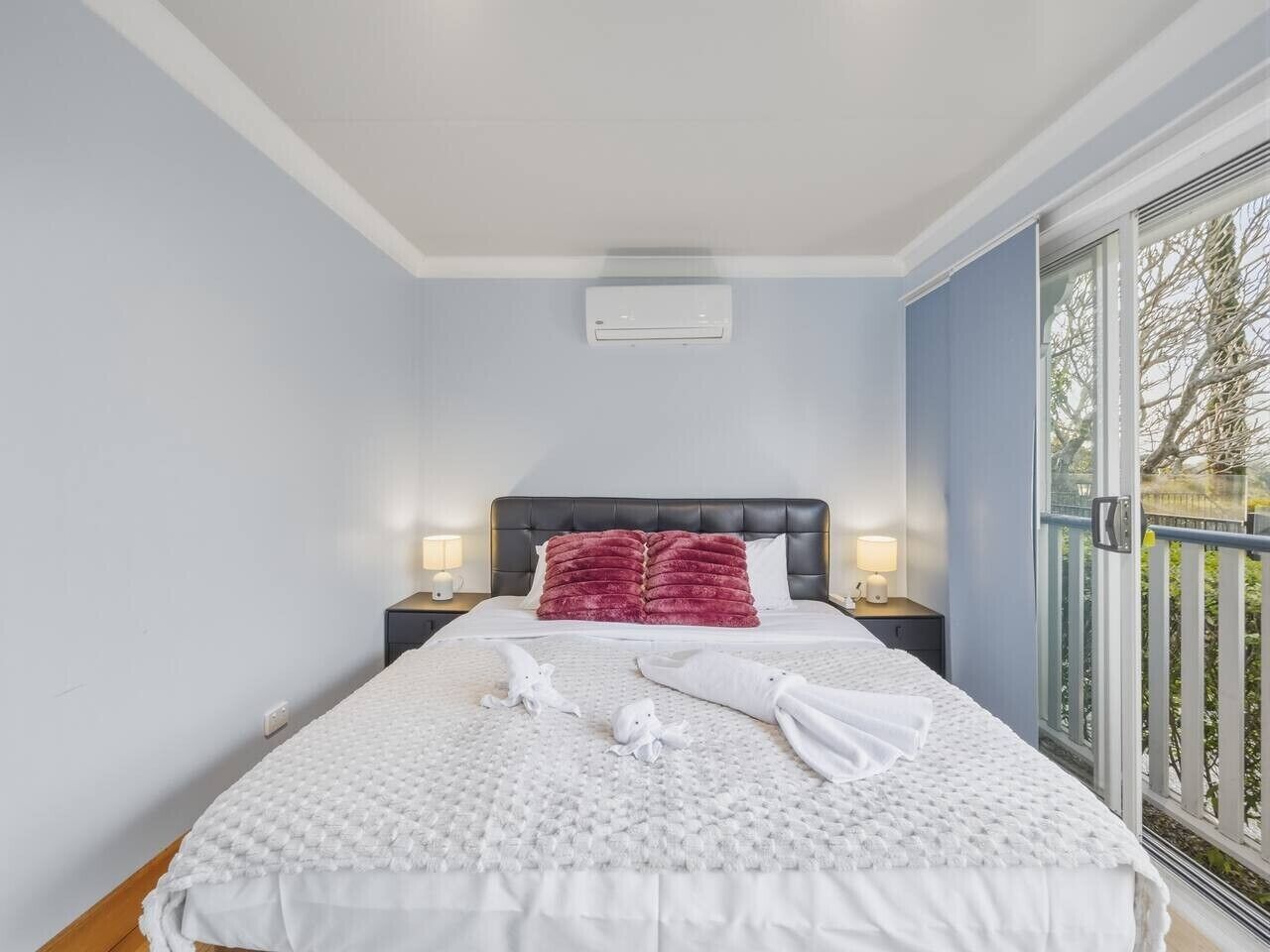Una camera d'albergo con un letto, un comodino, una finestra vista e un climatizzatore a soffitto.